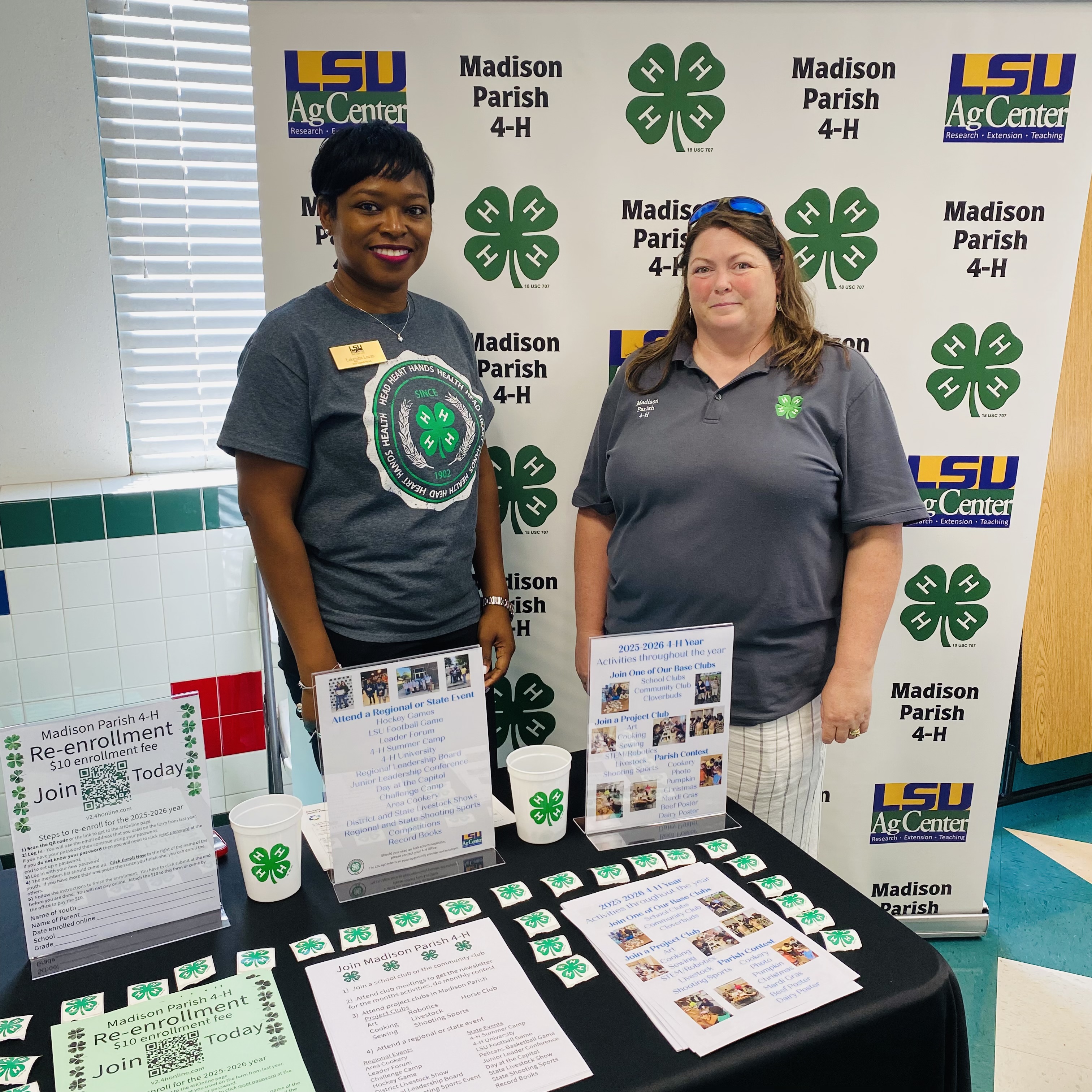 Two women standing behind a table filled with 4-H items.